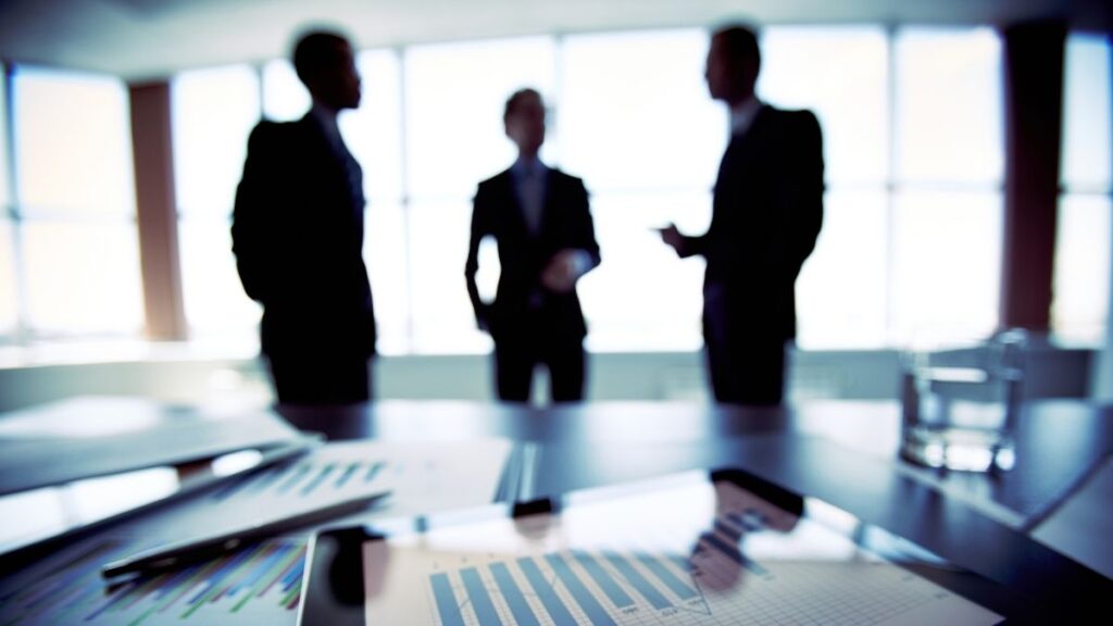 Business leaders discussing strategy over financial reports in a meeting room.
